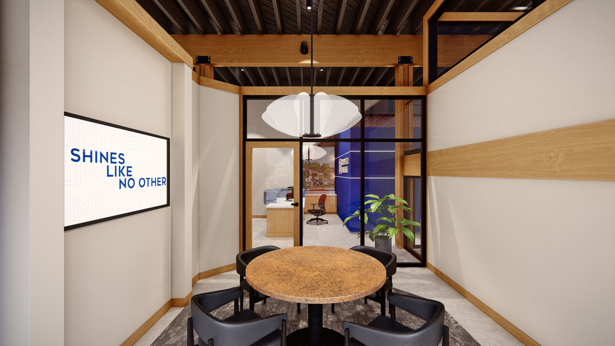 Small conference room at Coldwell Banker in The Shops, Coeur d'Alene, Idaho, featuring a round weathered copper table with black chairs, a digital display with the message 'Shines Like No Other,' glass walls, and a view into an adjacent office area with bold blue accents.