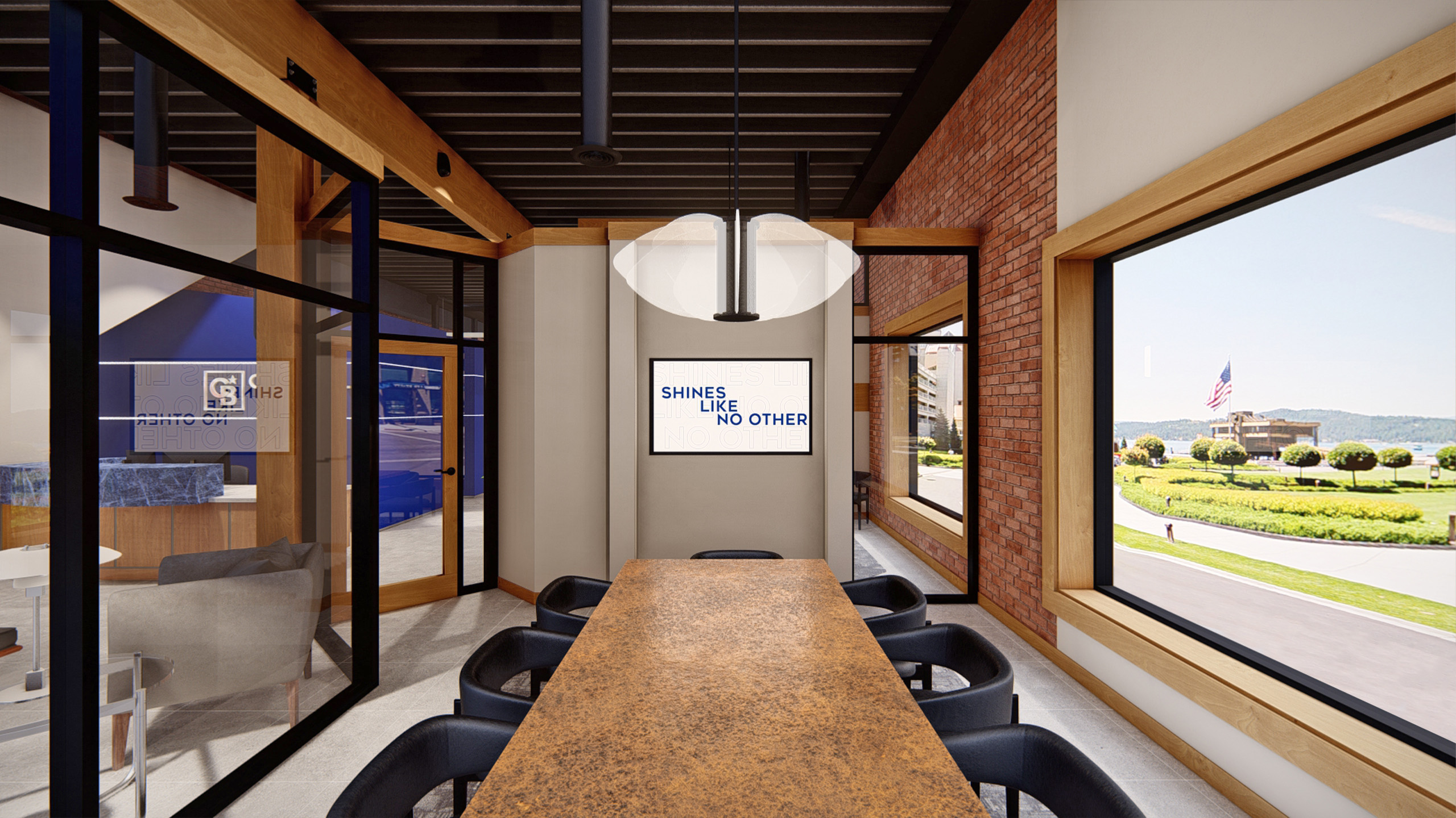 Conference room at Coldwell Banker in The Shops, Coeur d'Alene, Idaho, featuring a long weathered copper table, black chairs, a large window overlooking a landscaped roundabout with an American flag, and a monitor displaying the message 'Shines Like No Other'.