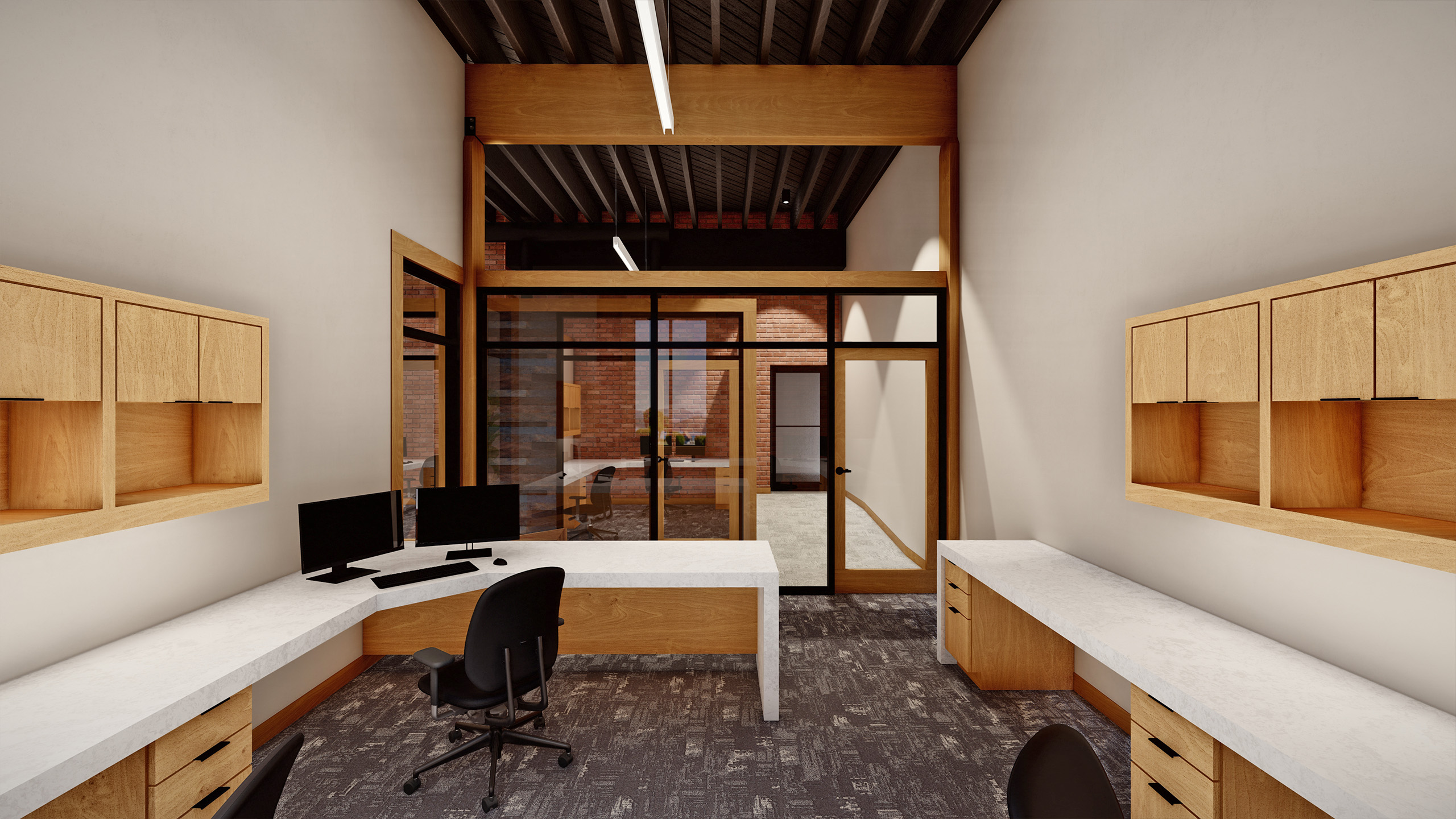 Interior office at Coldwell Banker in The Shops, Coeur d'Alene, Idaho, showing a workspace with built-in wood cabinetry, white countertops, dual computer monitors, and glass walls with views into adjacent brick-walled offices.